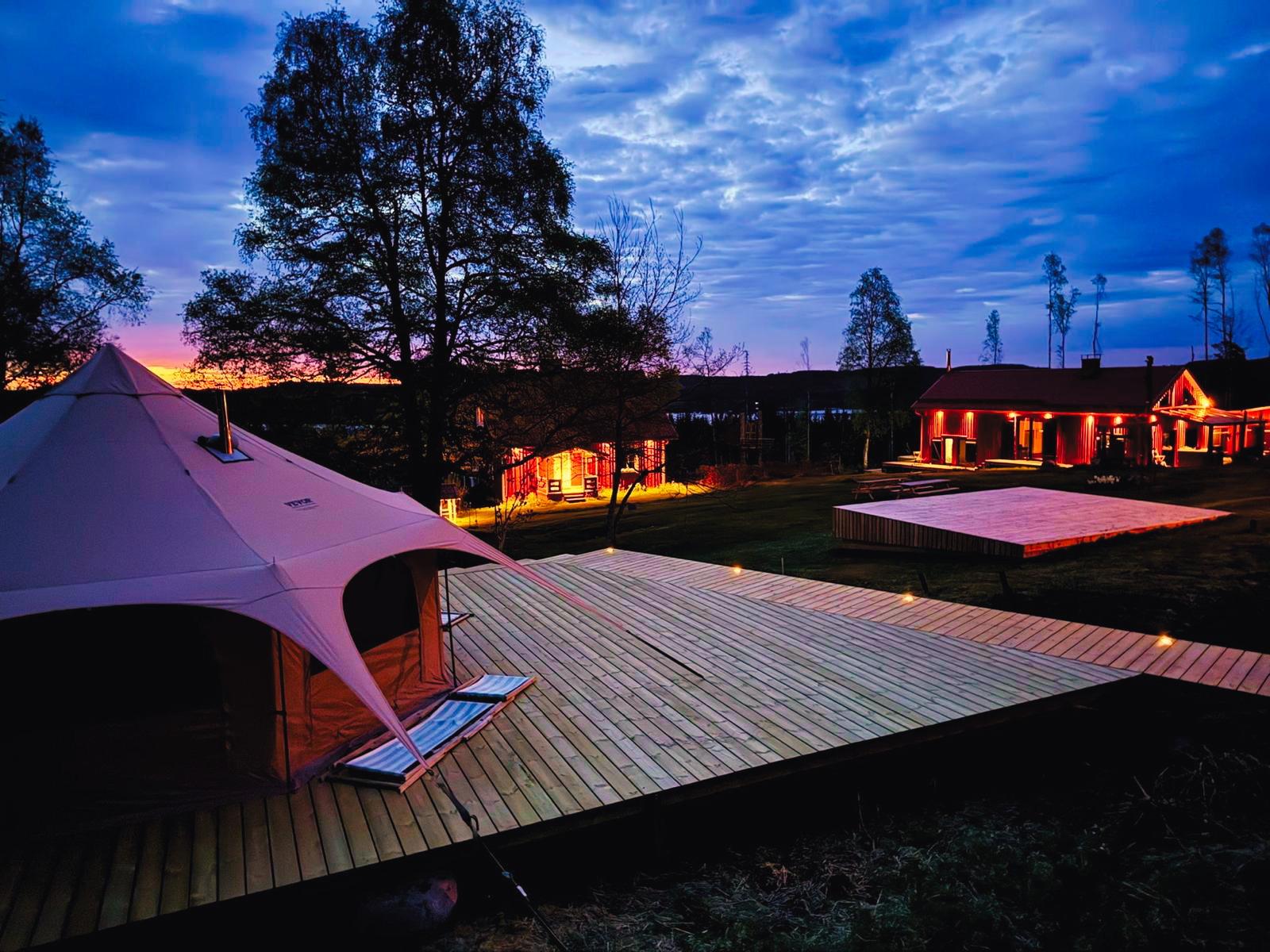 Glamping Zelt und beleuchtete Holzdecks am Abend